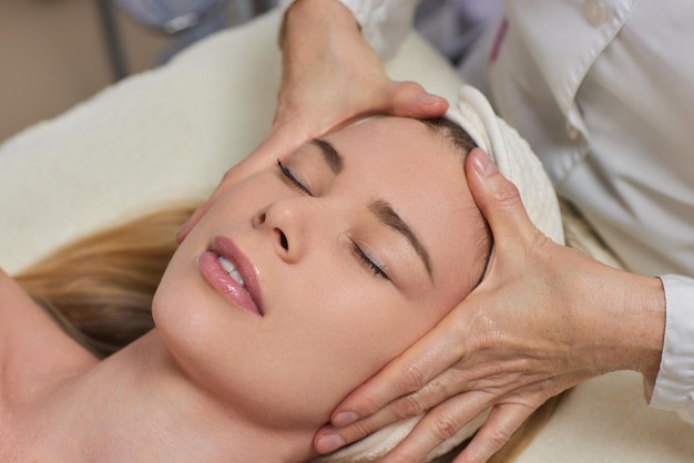 Mujer recibiendo masaje bucal facial en un salón de bellezaConcepto de belleza y cuidado de la piel con una mujer hermosa Mujer de mediana edad relajada con masaje para lifting facial