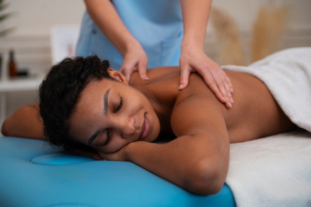 Foto mujer recibiendo un masaje de espalda en un centro de rehabilitación