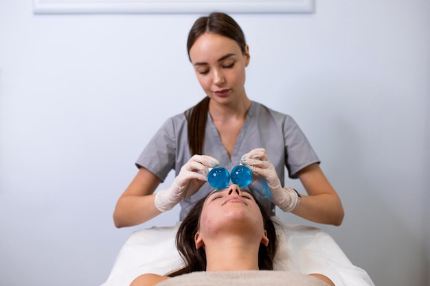 Mujer recibiendo masaje facial con bolas de cristal en salón de belleza