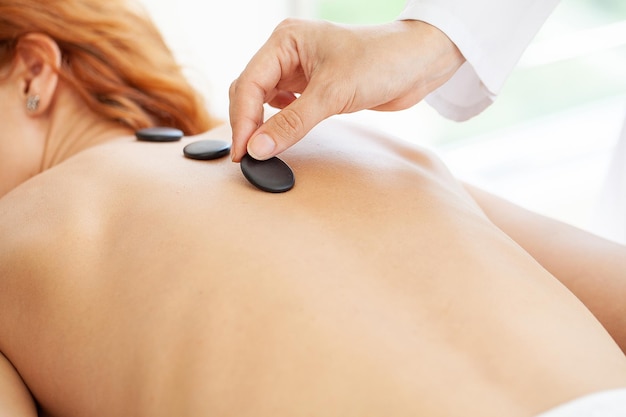 Mujer recibiendo un masaje con piedras calientes.