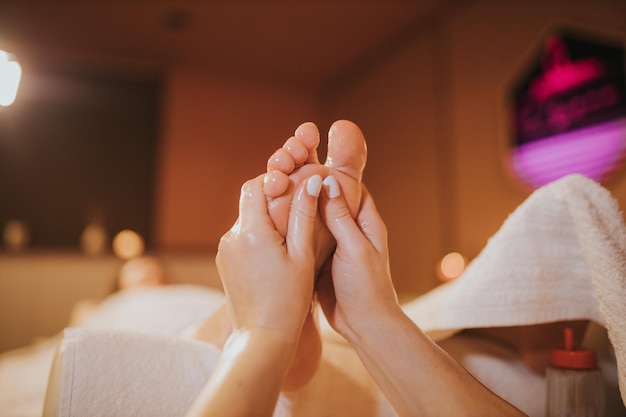 Mujer recibiendo un masaje profesional de pies en un salón de belleza - concepto de tratamiento de belleza