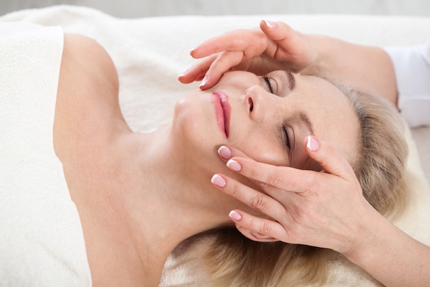 Mujer recibiendo masajes para rostro y cuello en el salón de spa