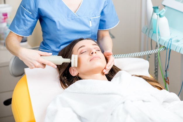 Mujer recibiendo peeling de cepillo profesional en la oficina de cosmetología