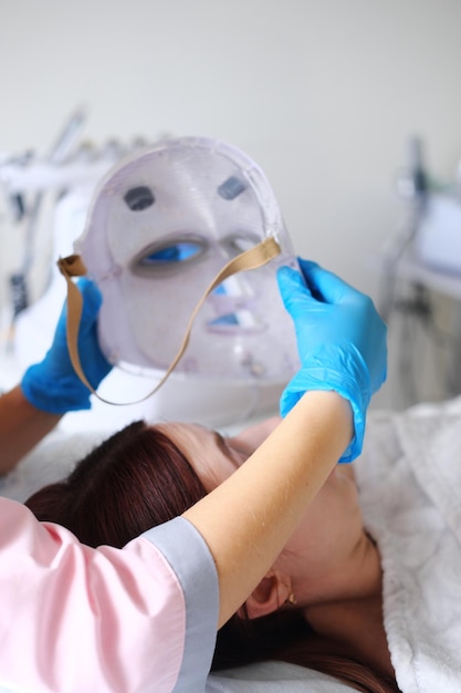 Mujer recibiendo procedimiento cosmético con terapia de fotones de máscara facial led
