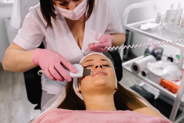 Mujer recibiendo terapia de limpieza con un equipo de ultrasonidos profesional en la oficina de cosmetología