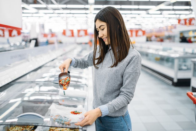 Mujer recoge paquete de verduras congeladas