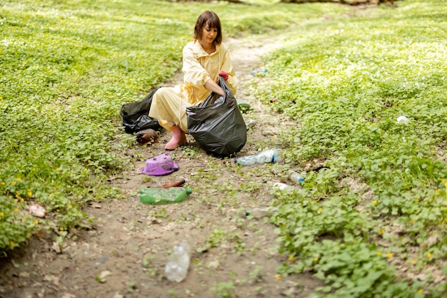 Mujer recogiendo basura plástica esparcida en el bosque