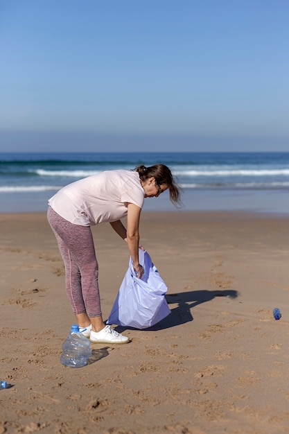 Mujer recogiendo basura y plásticos limpiando la playa