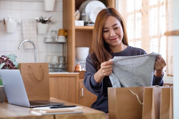 Una mujer recogiendo ropa de una bolsa de compras para la entrega y el concepto de compras en línea