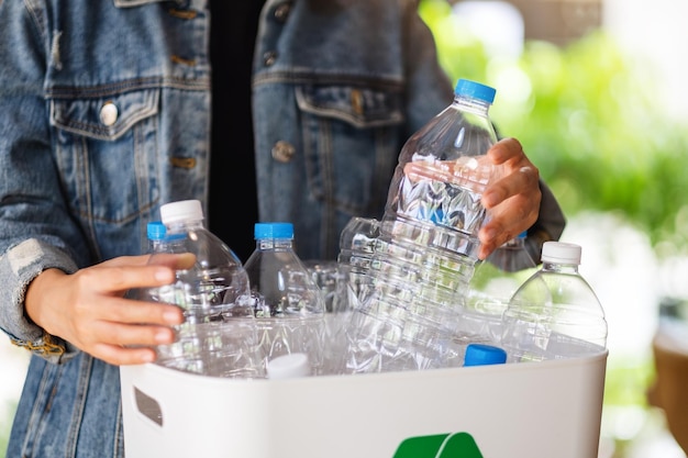 Una mujer recogiendo y separando botellas de plástico de basura reciclables en un cubo de basura en casa