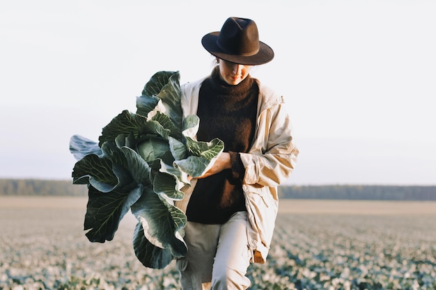 Mujer recogiendo vegetales de repollo en el campo Mujer agricultora trabajando en una granja orgánica Cosechando en la temporada de otoño