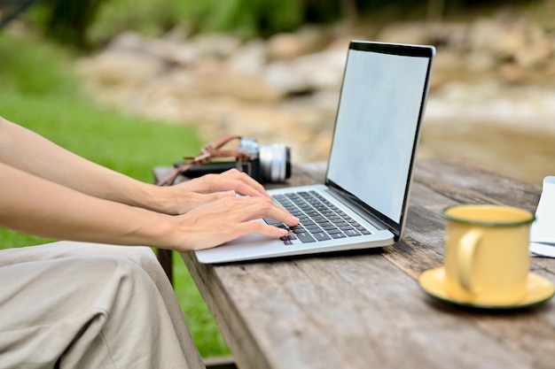 Mujer recortada relajándose en el parque verde natural y usando una computadora portátil