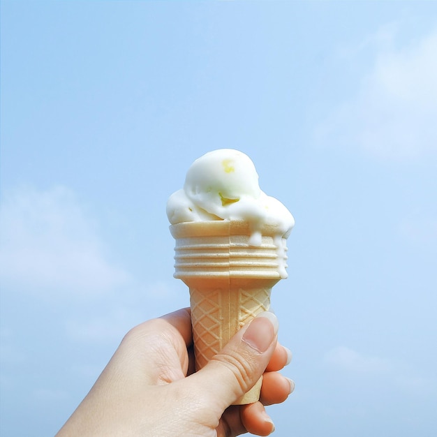 Mujer recortada sosteniendo un cono de helado contra el cielo