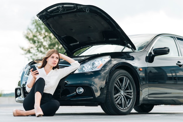 Foto mujer recostada en auto negro