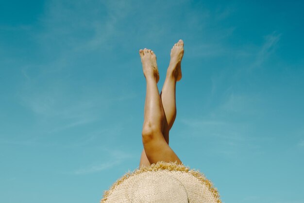 Foto mujer recostada en la playa de arena cruzando las piernas hasta las vacaciones de verano