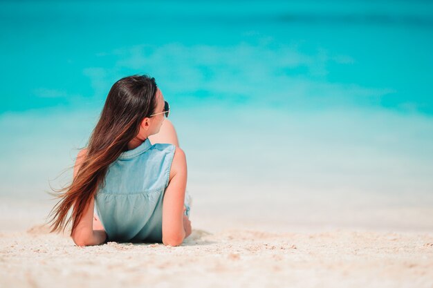 Mujer recostada en la playa disfrutando de las vacaciones de verano mirando al mar