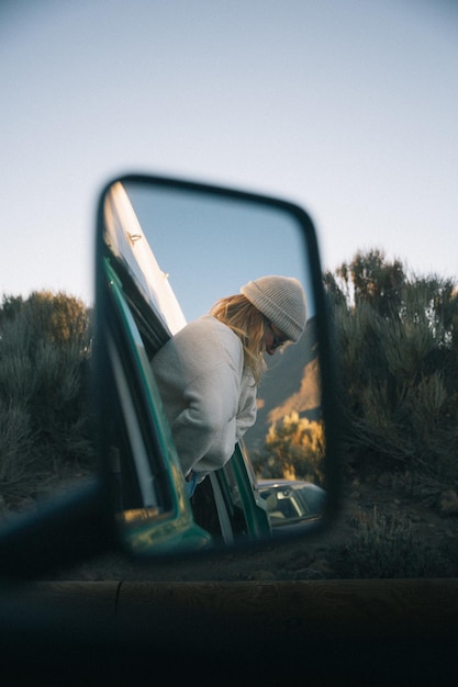 Foto mujer reflejada en el espejo lateral del coche