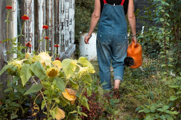 mujer con regadera trabajando en el jardín en el campo en verano