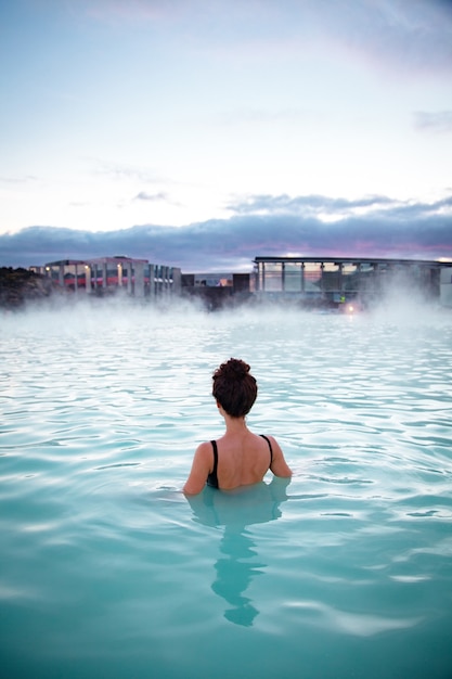 La mujer se relaja y disfruta del spa en la laguna azul de aguas termales en el hielo