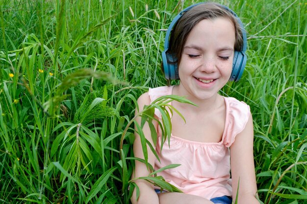 Mujer relajada acostada en la hierba escuchando música con auriculares en un parque