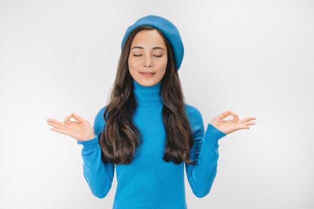 Mujer relajada con un aspecto elegante sosteniendo los dedos juntos para la meditación aislada sobre el fondo blanco