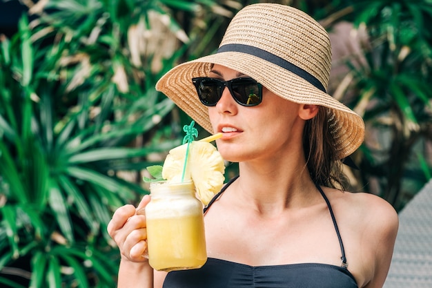 Mujer relajada en bikini bebiendo cóctel de piña