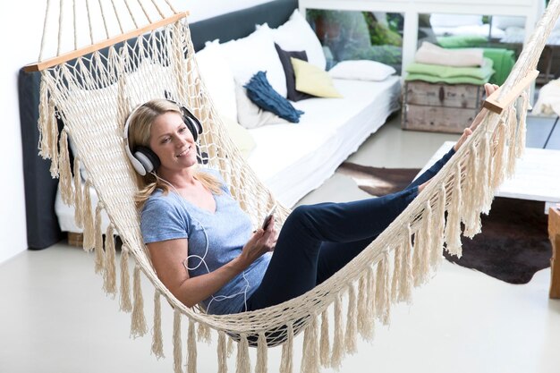 Mujer relajada en casa tumbada en una hamaca escuchando música