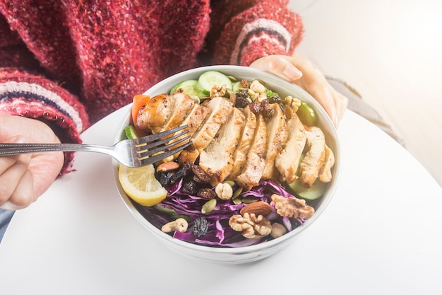 Mujer relajada disfrutando de ensalada de pechuga de pollo en casa