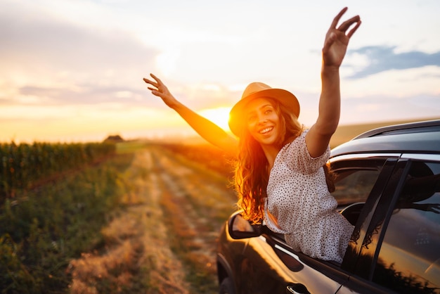 Mujer relajada y feliz en un viaje de verano, vacaciones de viaje, inclinándose por la ventana del coche, estilo de vida.