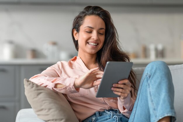 Foto mujer relajada navegando en la tableta en un ambiente hogareño acogedor