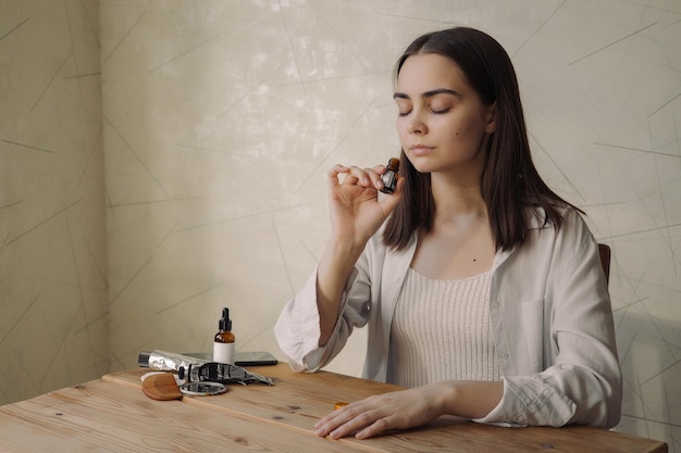 Mujer relajada con los ojos cerrados oliendo fragancia aromática de aceite esencial natural