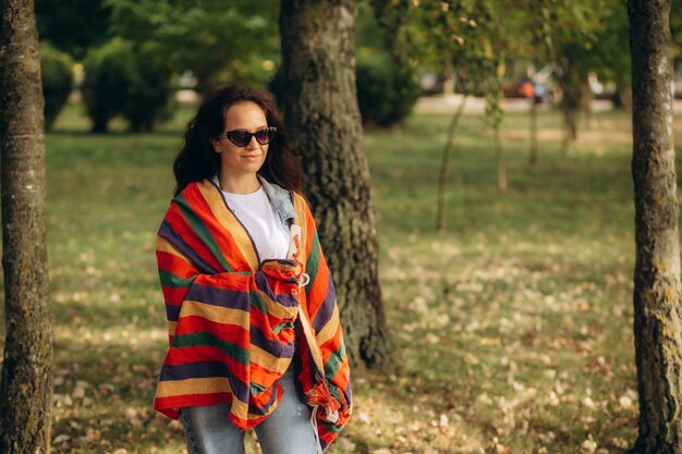 Mujer relajada respira aire fresco sosteniendo una taza de café para el desayuno sentada en una hamaca de cuerda en otoño en un bosque