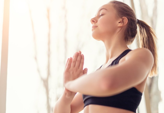 Mujer relajada respirando mientras medita por la ventana