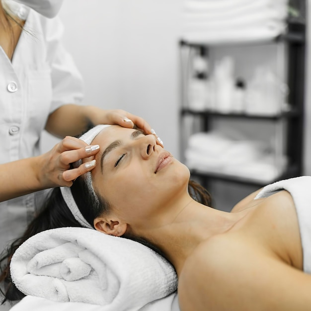 Foto mujer relajada en el salón de belleza ella está recibiendo terapia de toalla caliente para el cuerpo y la cara