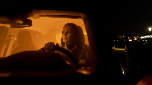 Foto mujer relajada y seria disfrutando de la conducción nocturna mientras está sentada en el coche y mirando hacia la señora del asiento del conductor