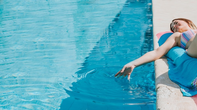 Foto mujer relajando al lado de piscina