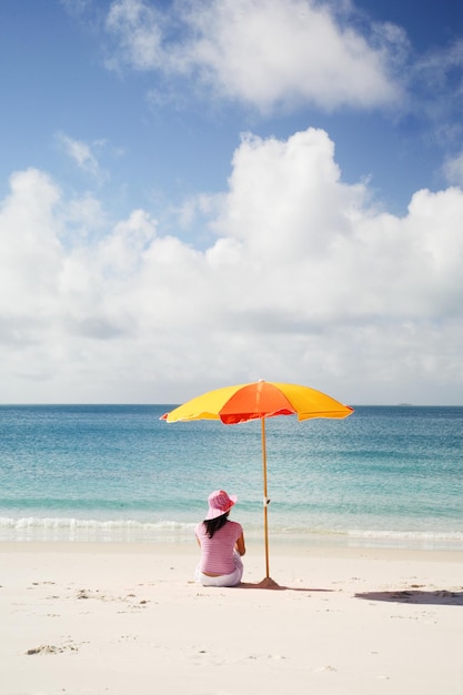 Mujer relajándose en la arena en la playa contra el cielo