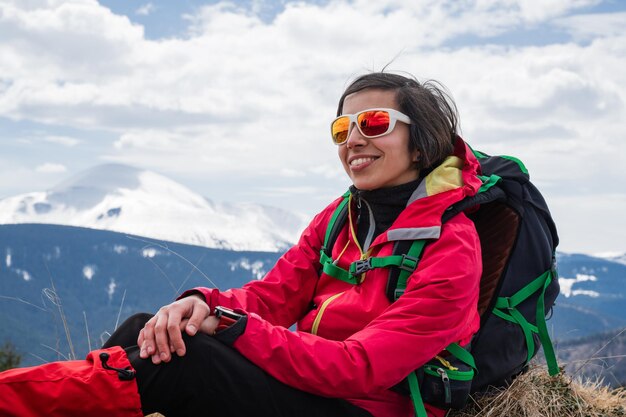 Mujer relajándose durante una caminata por la montaña sentada en la cima