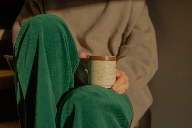 Mujer relajándose en las escaleras a la luz del sol con una taza de té