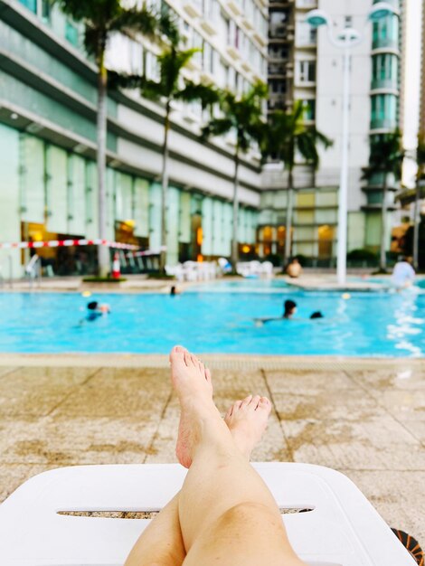 Foto mujer relajándose a la orilla de la piscina