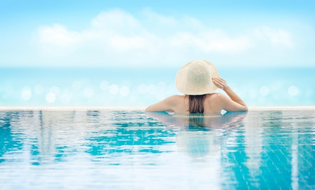 Mujer relajándose en la piscina frente al mar bokeh en vacaciones de verano Concepto de vacaciones soleado y caliente con espacio de copia