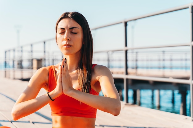 Mujer relajándose en posición de yoga en verano frente al mar