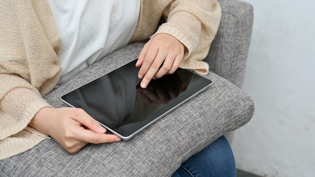 Mujer relajándose en la sala de estar de su casa y usando el panel táctil de la tableta digital