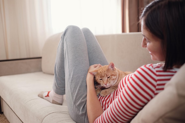 Mujer relajándose con su mascota de jengibre en un sofá Cozy scene hygge concept