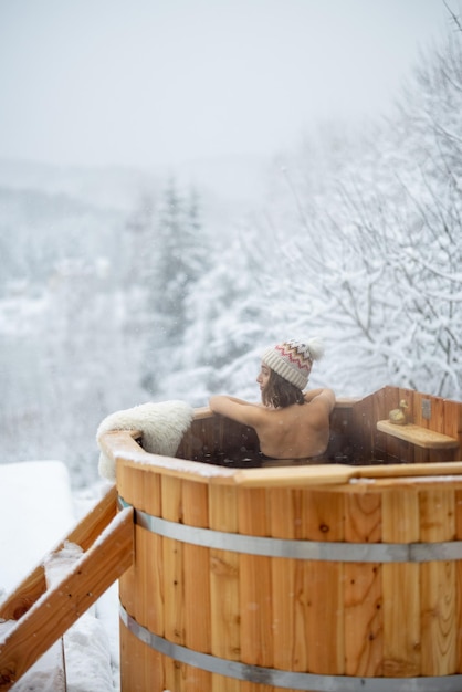 Mujer relajante en un baño caliente en las montañas nevadas