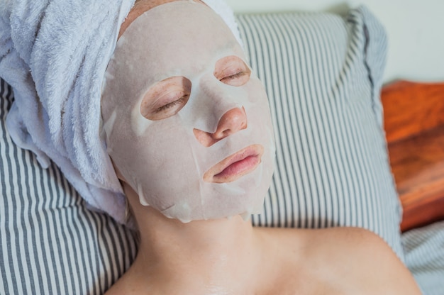 mujer relajante en la cama con una máscara facial