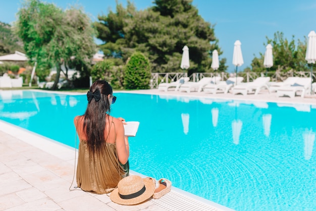 Mujer relajante junto a la piscina en un complejo hotelero de lujo disfrutando de vacaciones perfectas en la playa