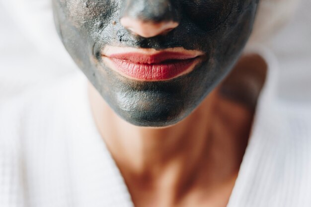 Mujer relajante con una mascarilla facial de carbón