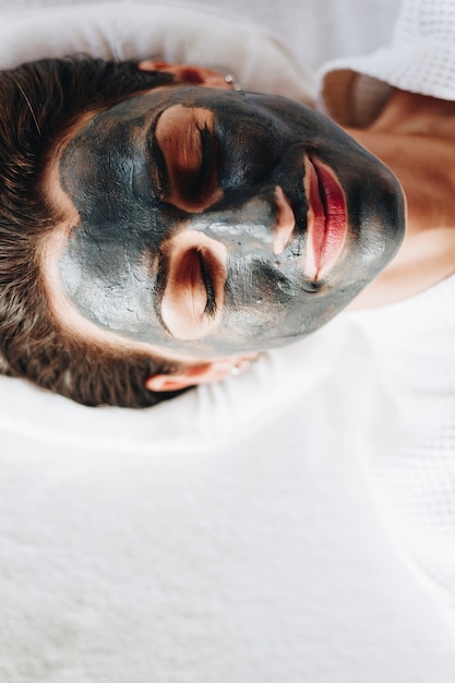 Mujer relajante con una mascarilla facial de carbón