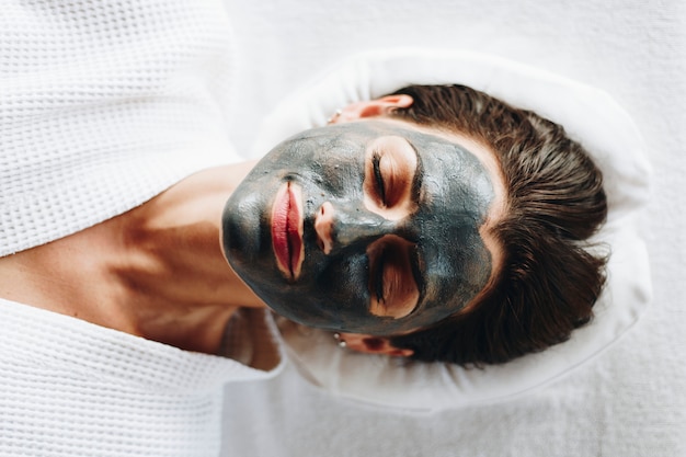 Mujer relajante con una mascarilla facial de carbón